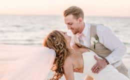 Groom dips bride on the beach