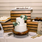 White wedding cake with roses and variety of cupcakes at a private estate in Naples, FL