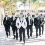 Groom and groomsmen with glasses on walking at the camera in Naples, FL