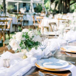 Wedding tablescape with gold chargers, white roses and votives