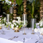 White roses and purple flowers in gold pots and long candles as wedding centerpiece at Hotel Escalante